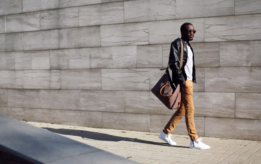 Black man holding satchel walking